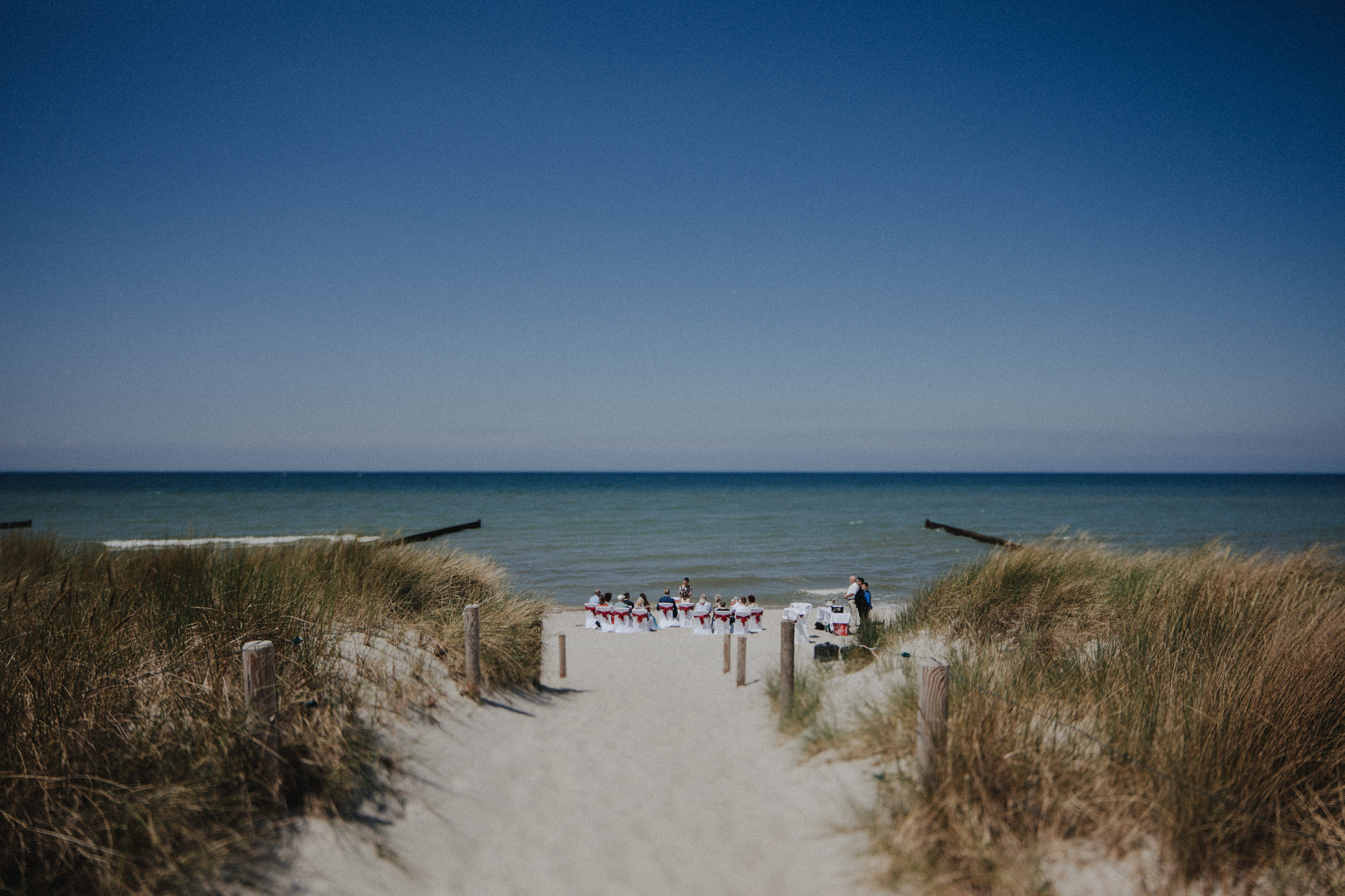 Strandhochzeit an der Ostsee. Es handelt sich um ein Foto aus einer Hochzeitsreportage, das von den beiden Hochzeitsfotografen Tom und Lia Fotografie aus Potsdam aufgenommen wurde. Die Hochzeit fand in Ahrenshoop direkt am Strand statt.