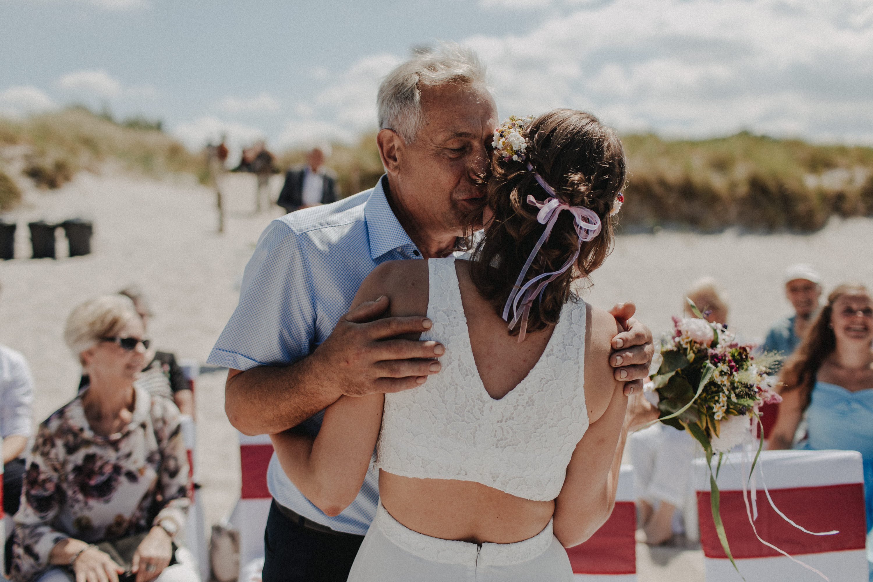 Strandhochzeit an der Ostsee. Es handelt sich um ein Foto aus einer Hochzeitsreportage, das von den beiden Hochzeitsfotografen Tom und Lia Fotografie aus Potsdam aufgenommen wurde. Die Hochzeit fand in Ahrenshoop direkt am Strand statt.