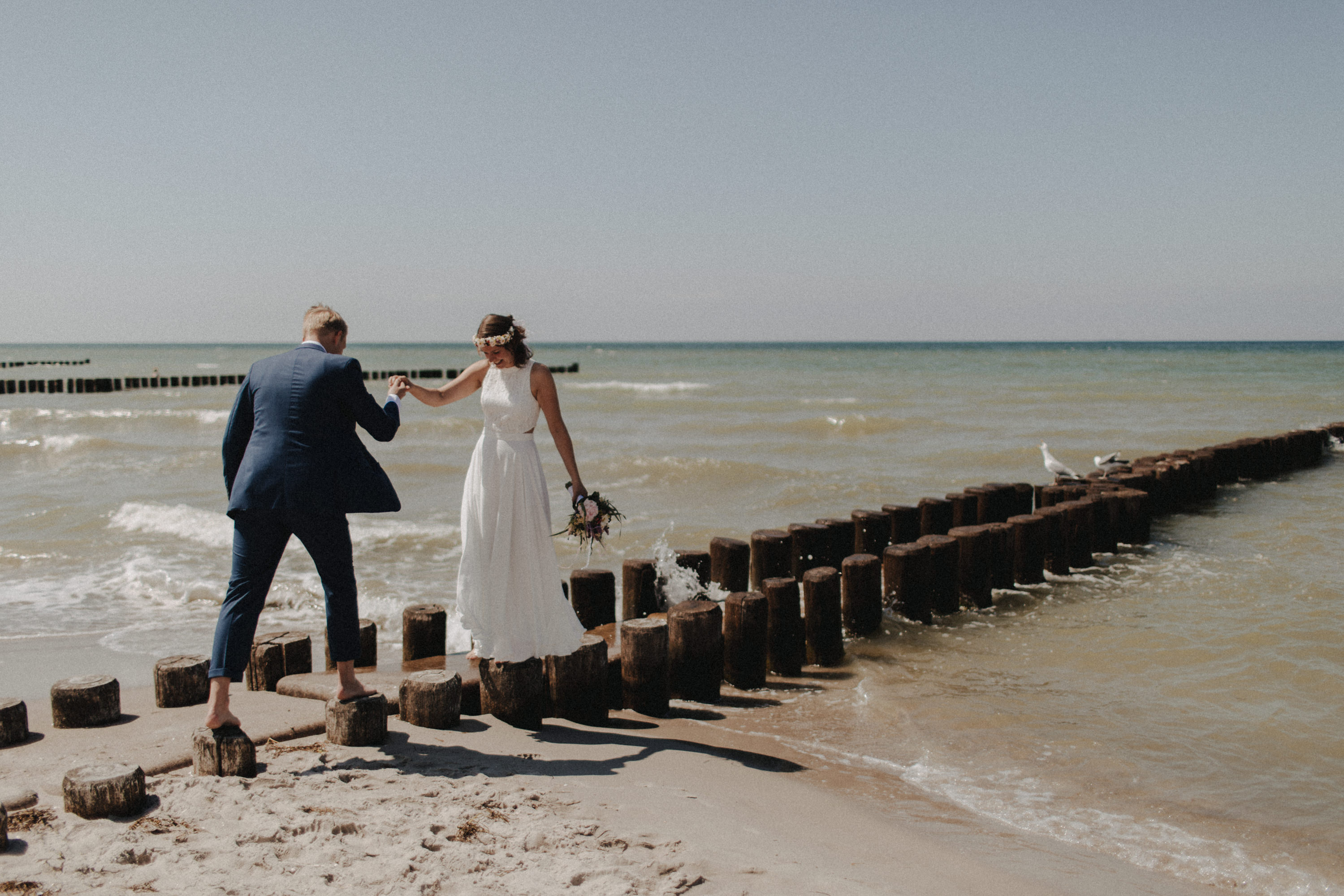 Strandhochzeit an der Ostsee. Es handelt sich um ein Foto aus einer Hochzeitsreportage, das von den beiden Hochzeitsfotografen Tom und Lia Fotografie aus Potsdam aufgenommen wurde. Die Hochzeit fand in Ahrenshoop direkt am Strand statt.