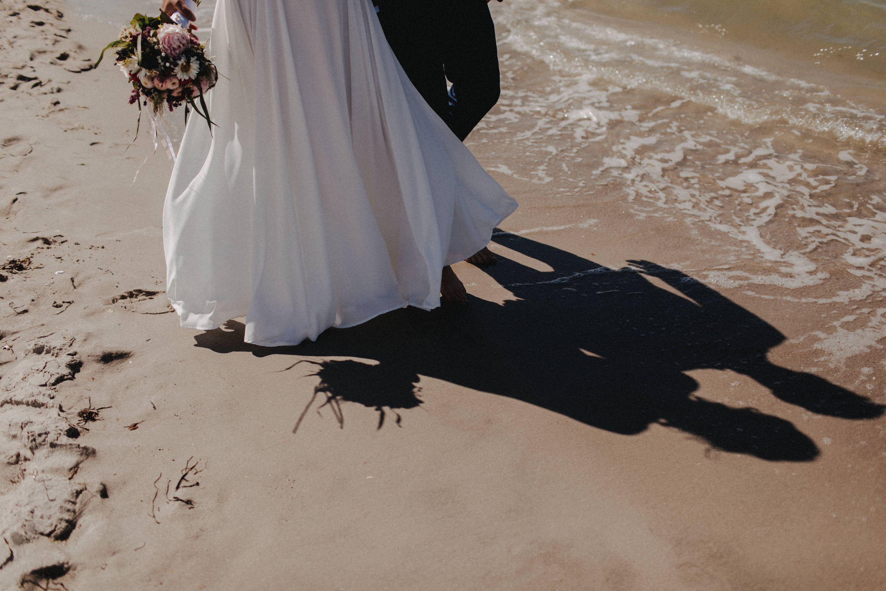 Strandhochzeit an der Ostsee. Es handelt sich um ein Foto aus einer Hochzeitsreportage, das von den beiden Hochzeitsfotografen Tom und Lia Fotografie aus Potsdam aufgenommen wurde. Die Hochzeit fand in Ahrenshoop direkt am Strand statt.