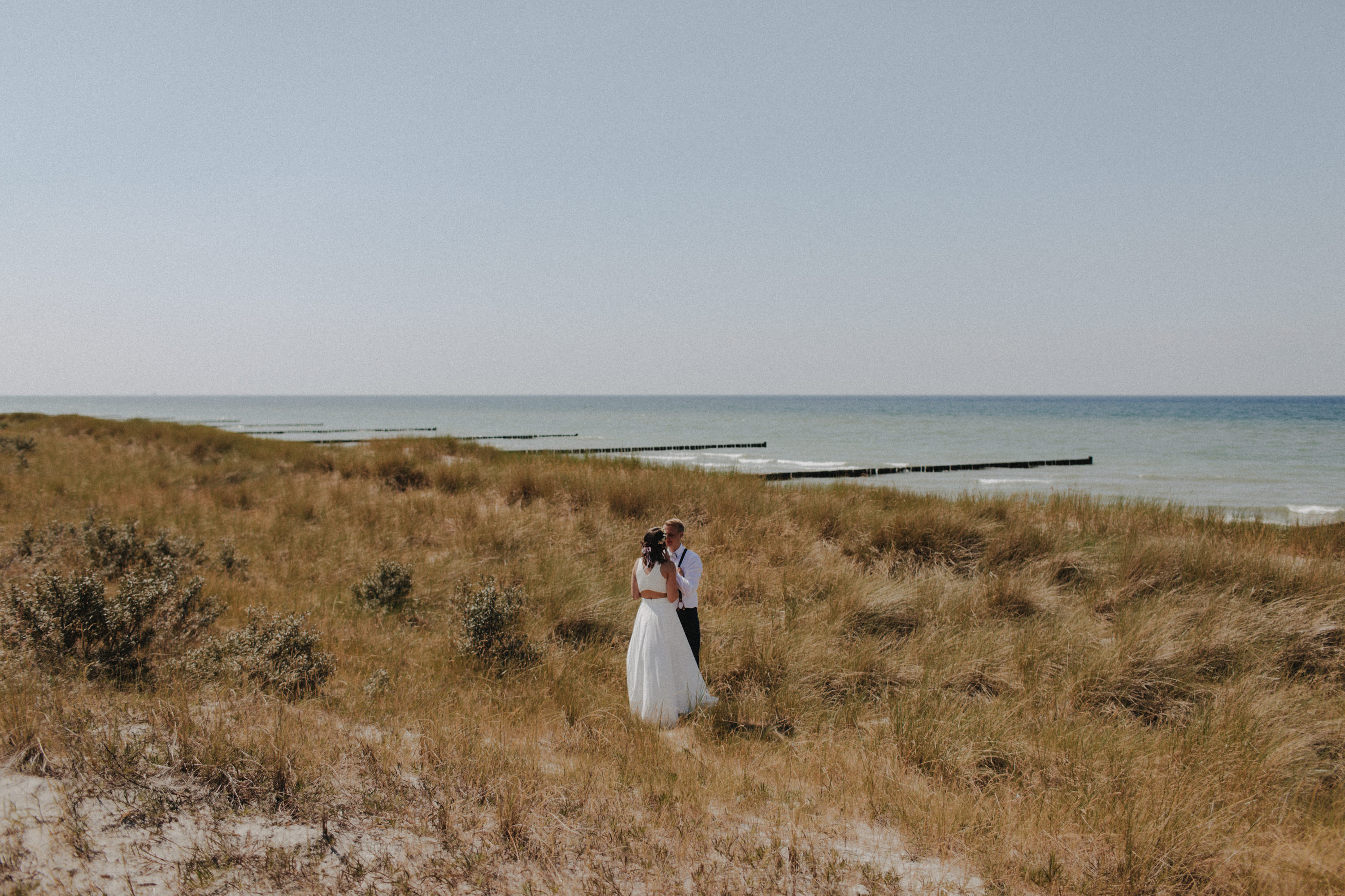 Strandhochzeit an der Ostsee. Es handelt sich um ein Foto aus einer Hochzeitsreportage, das von den beiden Hochzeitsfotografen Tom und Lia Fotografie aus Potsdam aufgenommen wurde. Die Hochzeit fand in Ahrenshoop direkt am Strand statt.