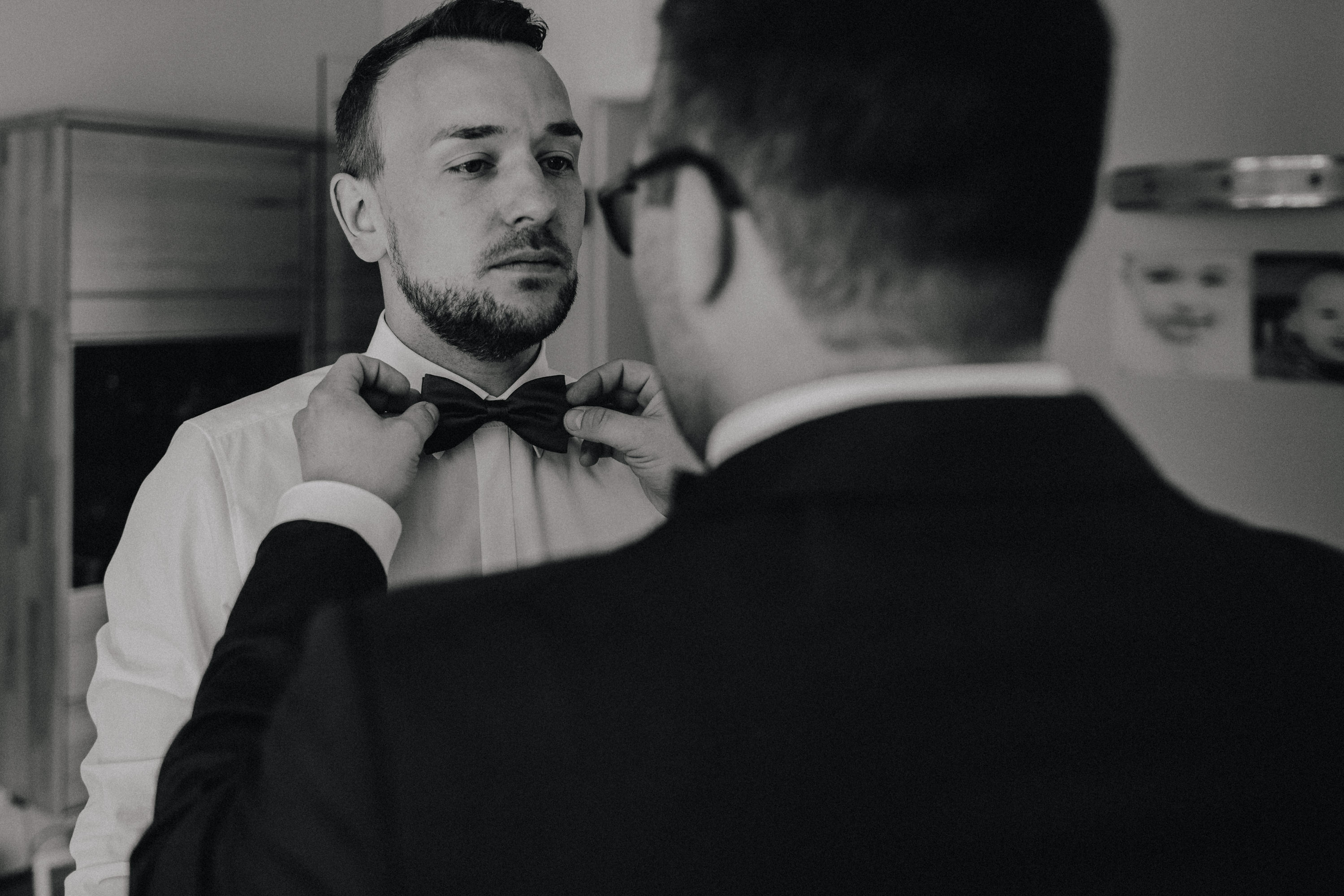 Dieses Foto ist Teil einer Hochzeitsreportage, die von den Hochzeitsfotografen Tom und Lia aus Potsdam aufgenommen wurde. Zu sehen ist der Bräutigam während des Getting Readys, der sich mit seinen besten Freunden anzieht.