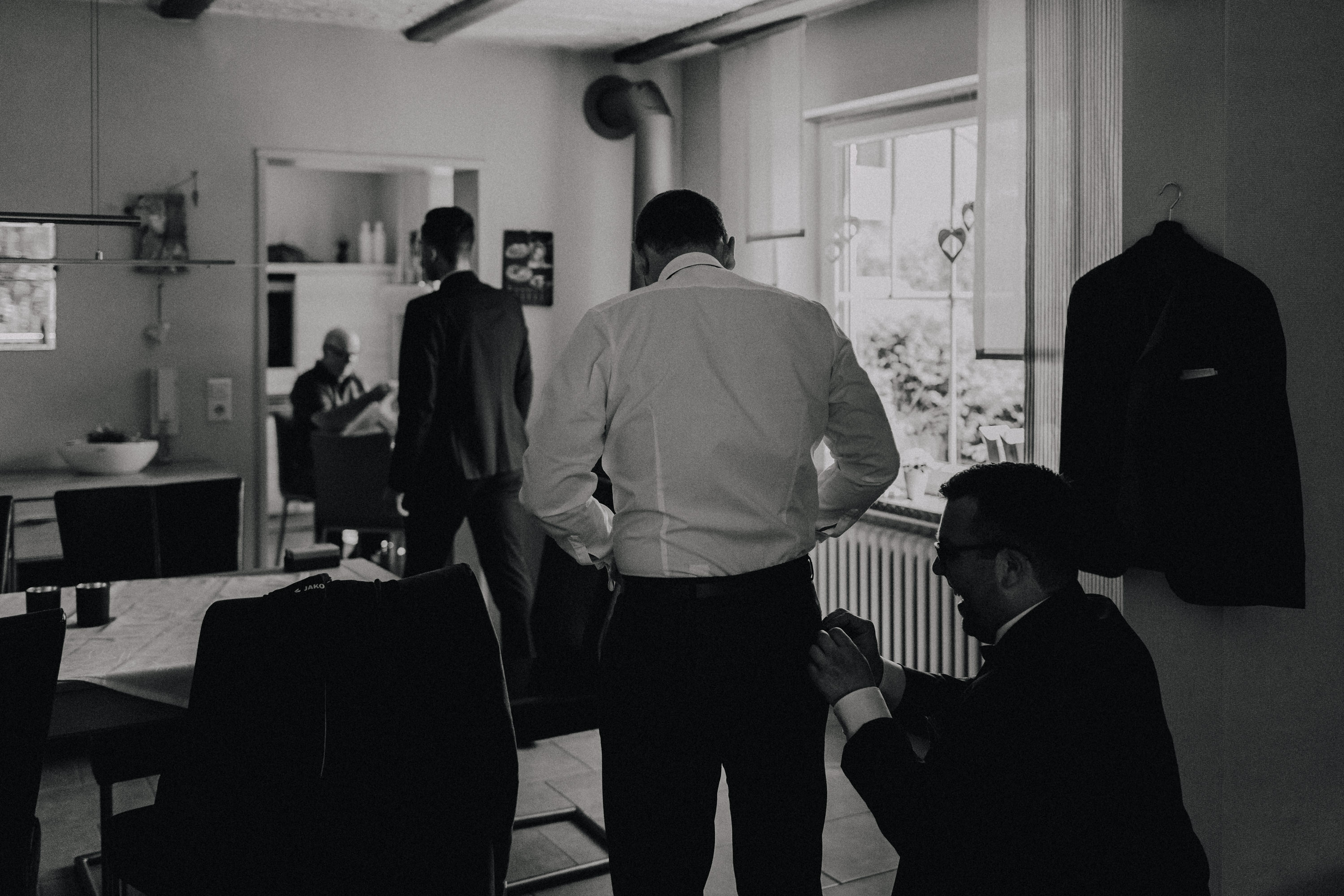 Dieses Foto ist Teil einer Hochzeitsreportage, die von den Hochzeitsfotografen Tom und Lia aus Potsdam aufgenommen wurde. Zu sehen ist der Bräutigam während des Getting Readys, der sich mit seinen besten Freunden anzieht.
