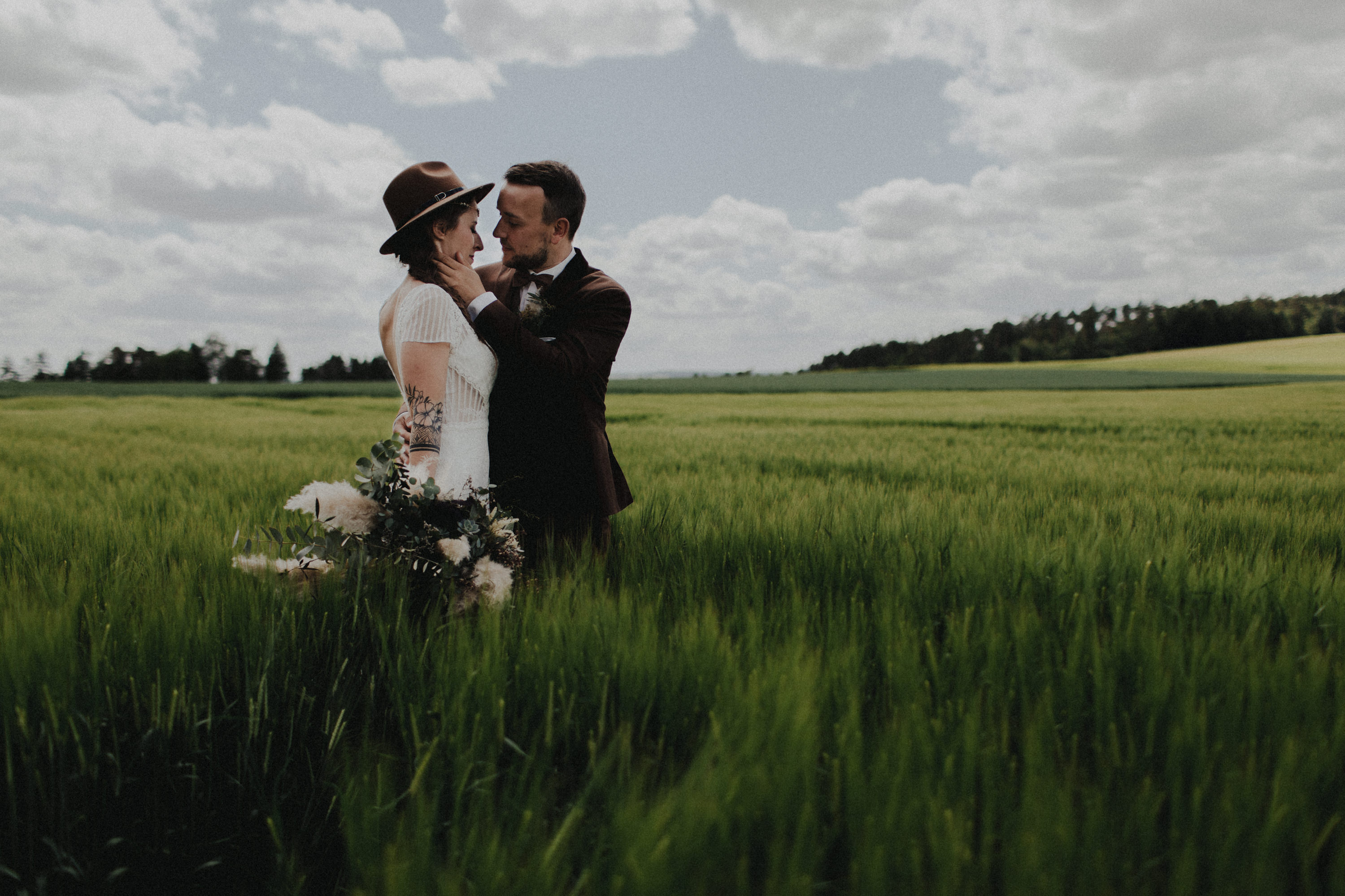 Dieses Foto ist Teil einer Hochzeitsreportage, die von den Hochzeitsfotografen Tom und Lia aus Potsdam aufgenommen wurde. Zu sehen ist das Brautpaar während des Brautpaar-Shootings in einem satt grünem Feld bei strahlendem Sonnenschein.