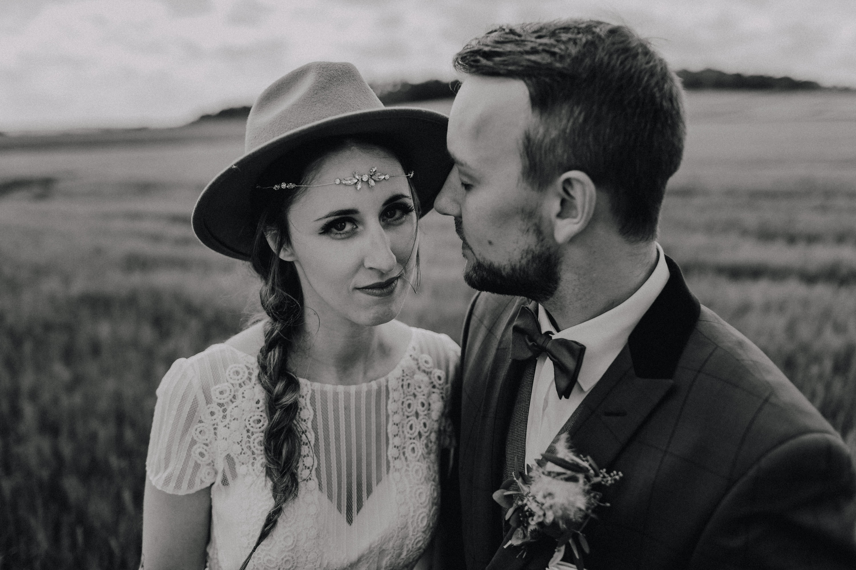 Dieses Foto ist Teil einer Hochzeitsreportage, die von den Hochzeitsfotografen Tom und Lia aus Potsdam aufgenommen wurde. Zu sehen ist das Brautpaar während des Brautpaar-Shootings in einem satt grünem Feld bei strahlendem Sonnenschein.